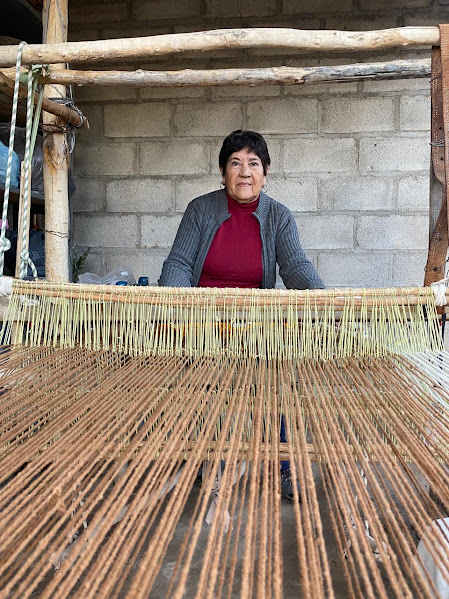 Una persona junto a un telar en su espacio de trabajo